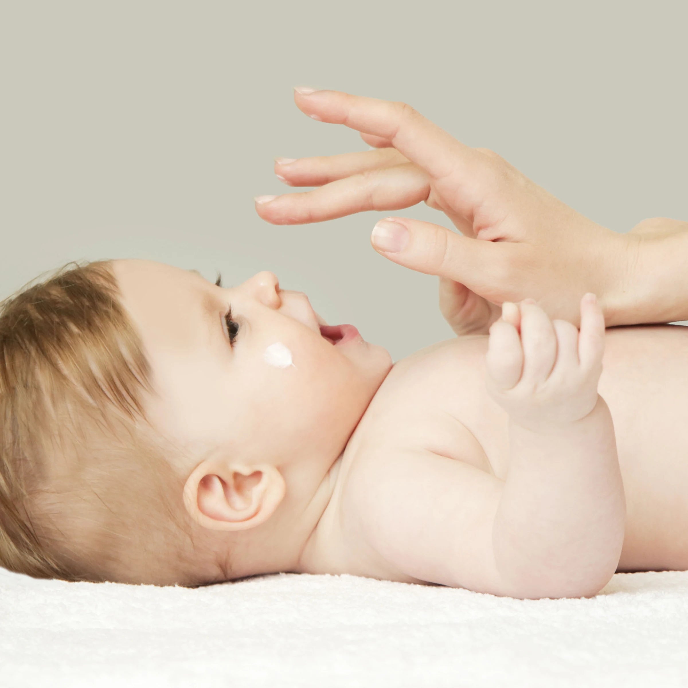 Mutter trägt Baby Gesichtscreme auf die Wange ihres Babys auf, parfümfreie Pflege von vujo