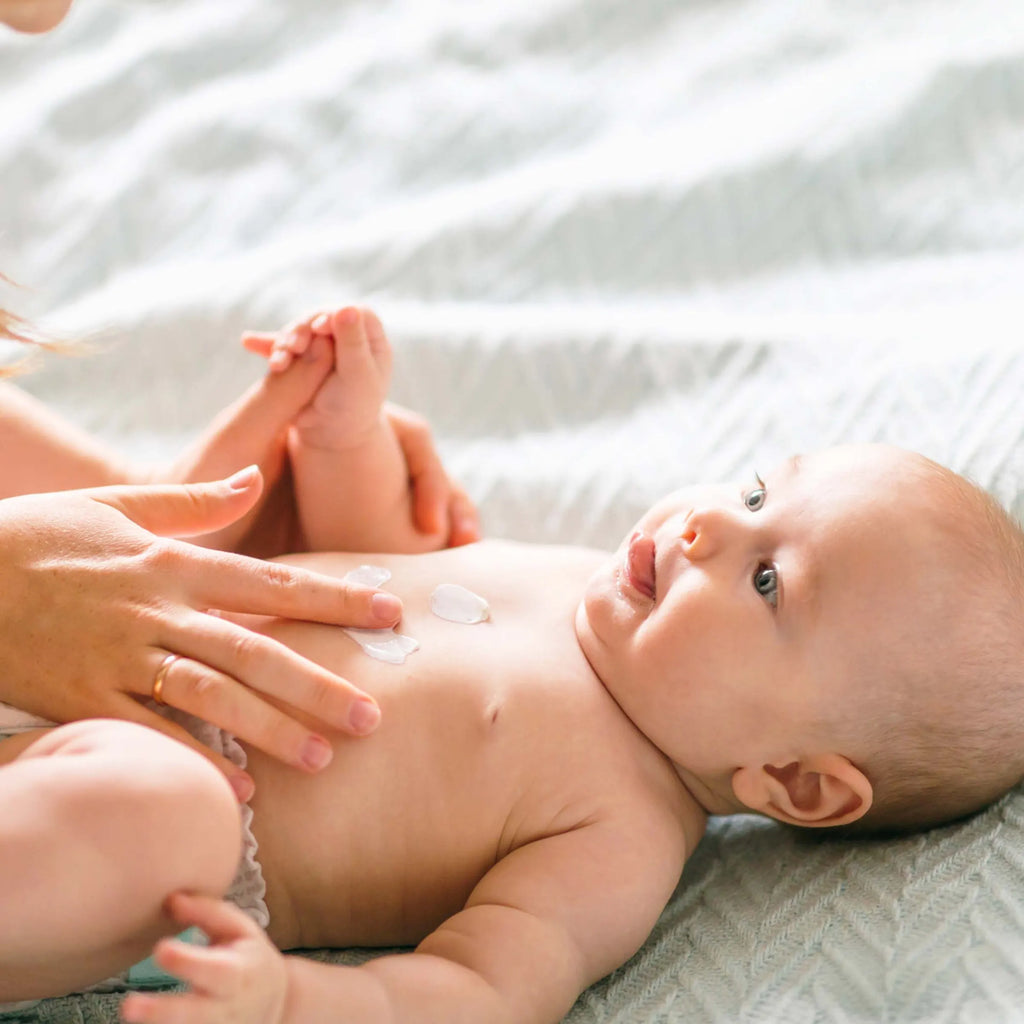 Mutter trägt Baby Bodylotion auf die Brust ihres Babys auf, parfümfreie Pflege von vujo