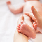 Mutter massiert mit parfümfreiem Babyöl die Füße ihres Babys, Babymassage mit vujo
